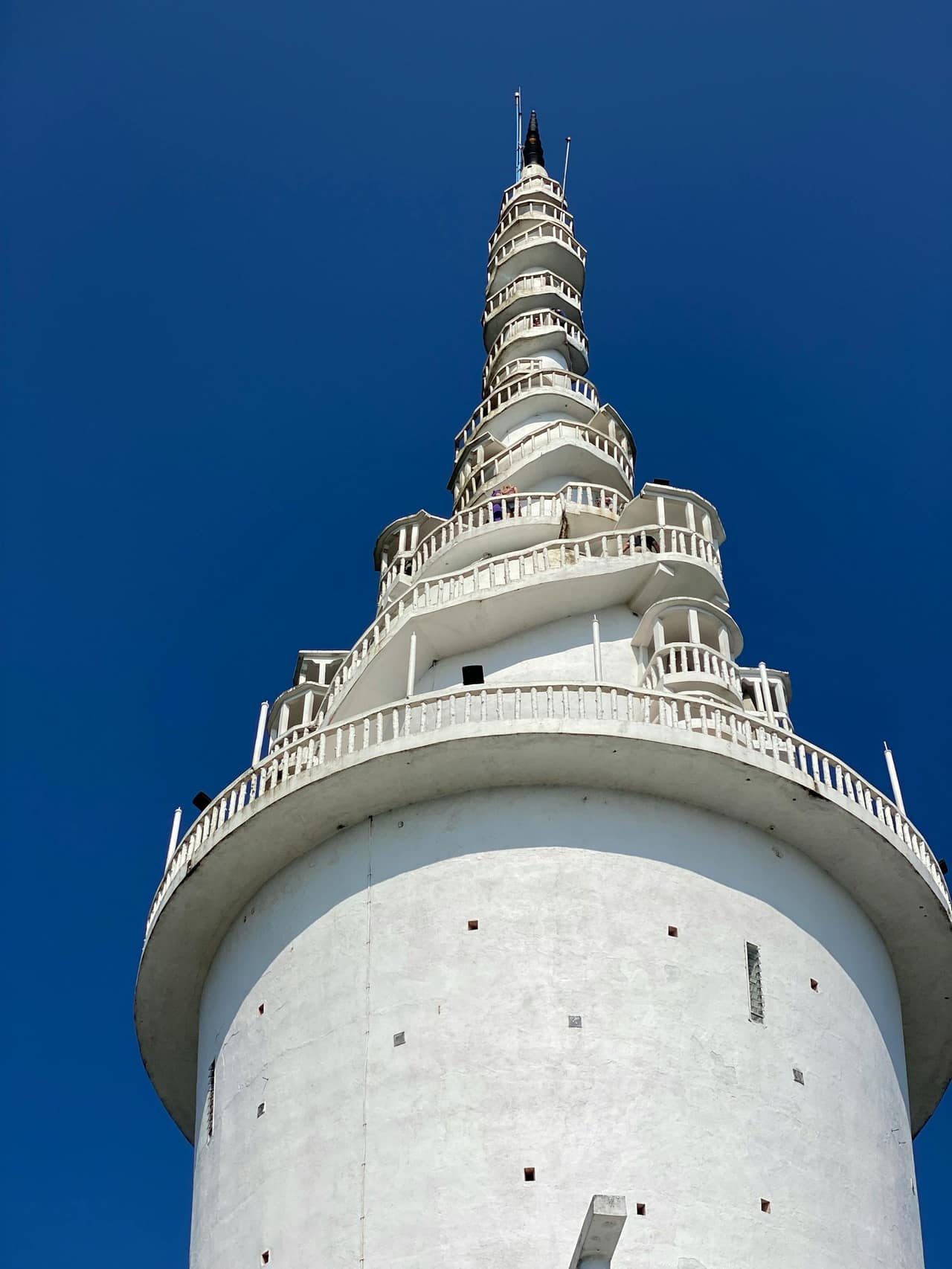 The white spiral tower of Ambuluwawa rising above forested hills near Gampola, Sri Lanka